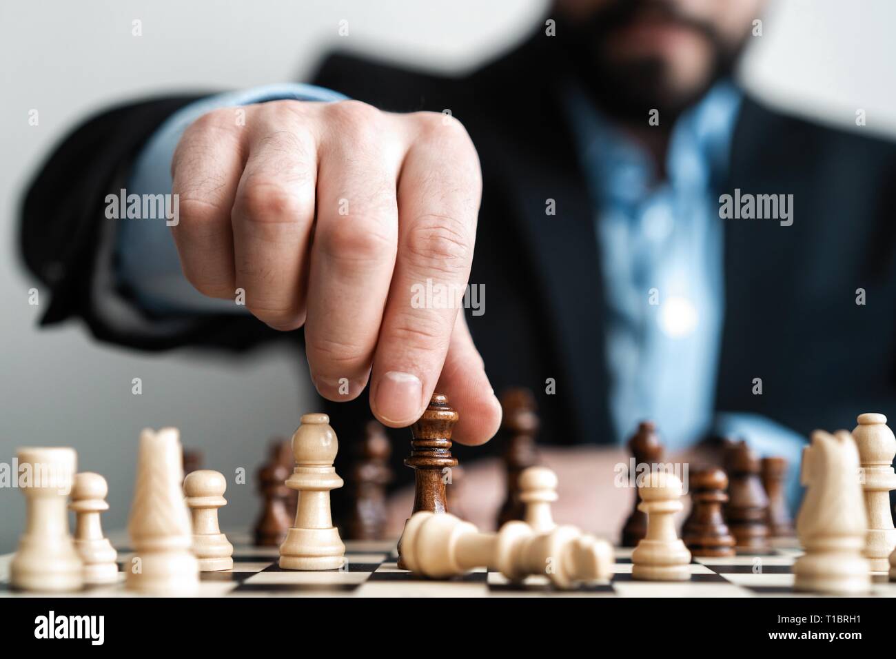 Close up of hands of a business man moving king golden chess to defeat  opponent the chess game is development analysis, strategy, and plan, the  management or leadership concept. 22804709 Stock Photo