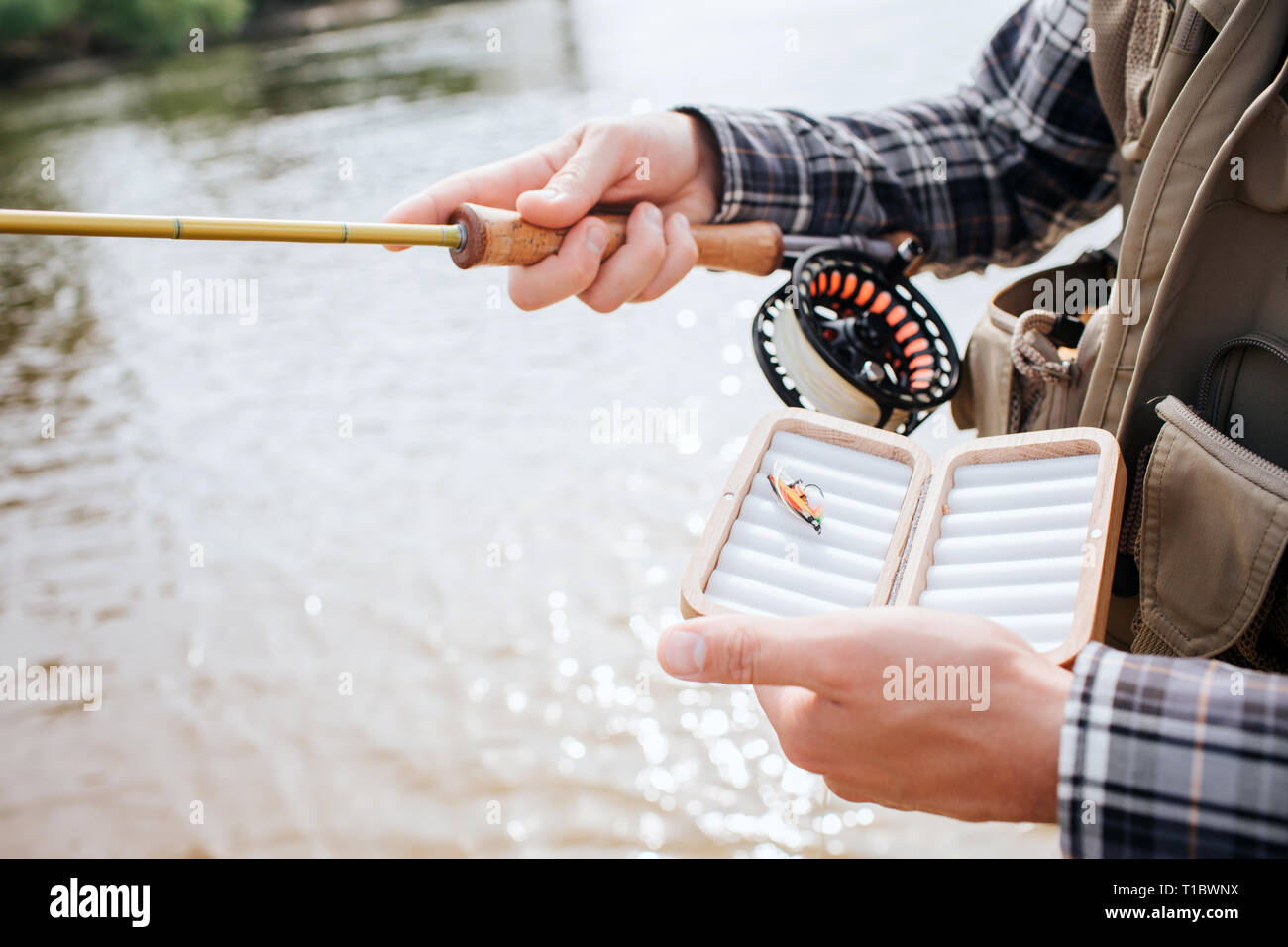 Cut view of man standing in water and holding spinning with reel in one hand  and a box with one artificial silicone fishing lure with the other one  Stock Photo - Alamy