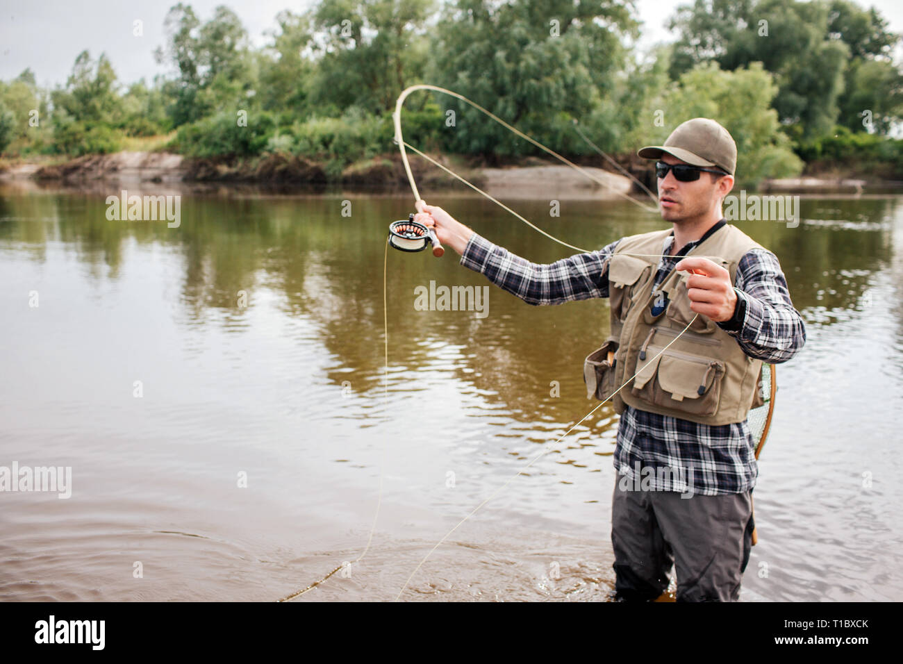 https://c8.alamy.com/comp/T1BXCK/serious-fisherman-stands-on-shallow-an-waving-with-fly-fishing-also-he-has-a-spoon-in-other-hand-guy-is-looking-to-the-left-he-is-concentrated-T1BXCK.jpg