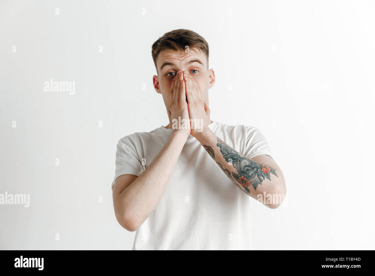 Why is that. Beautiful male half-length portrait isolated on gray studio backgroud. Young emotional surprised, frustrated and bewildered man. Human emotions, facial expression concept. Stock Photo