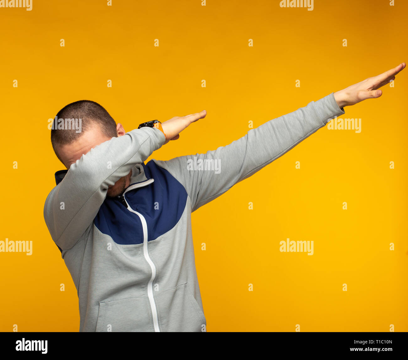 Man in hoodie show swag standing at orange background Stock Photo