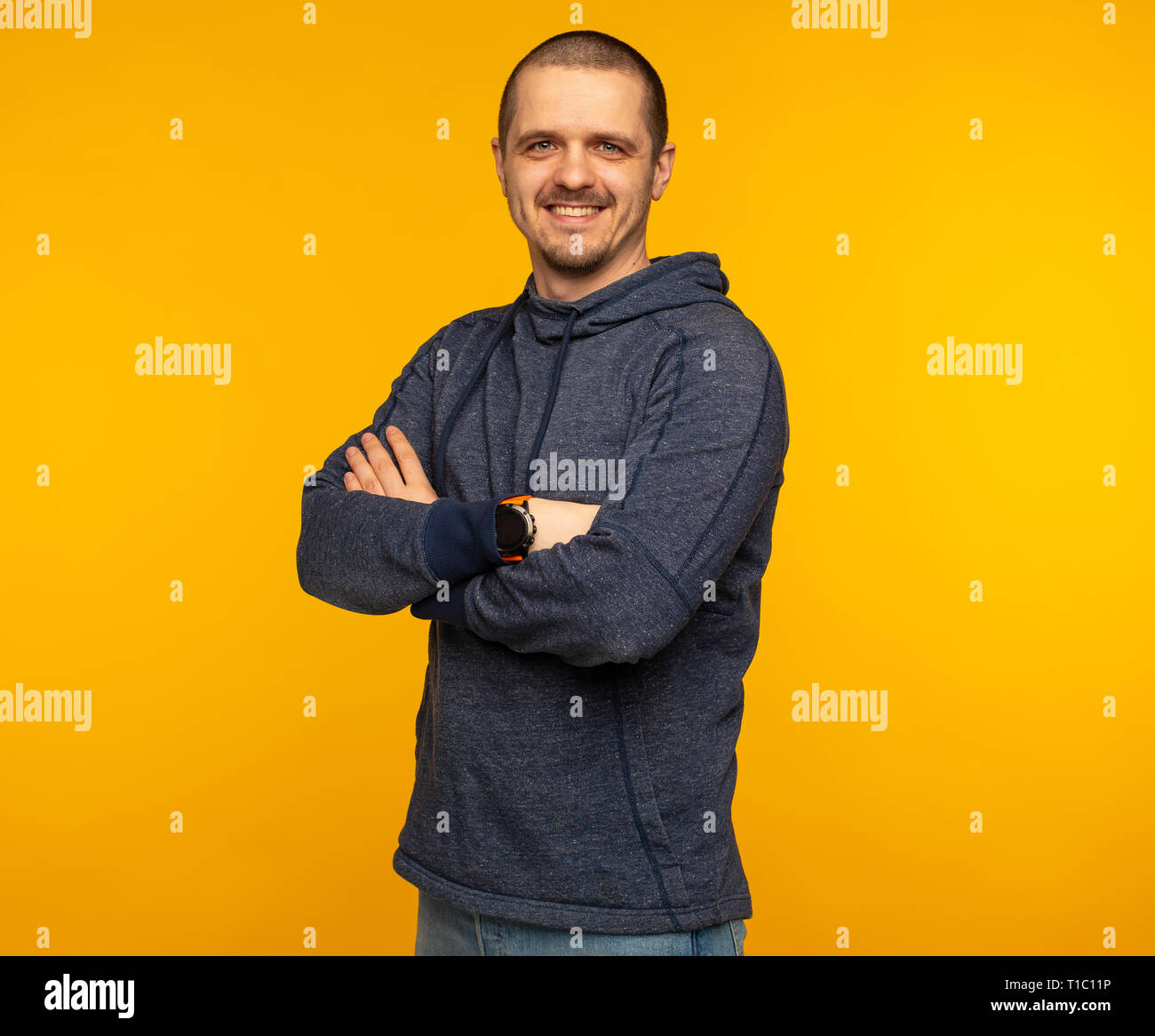 Man in hoodie with crossed arms smiling and looking in camera Stock Photo