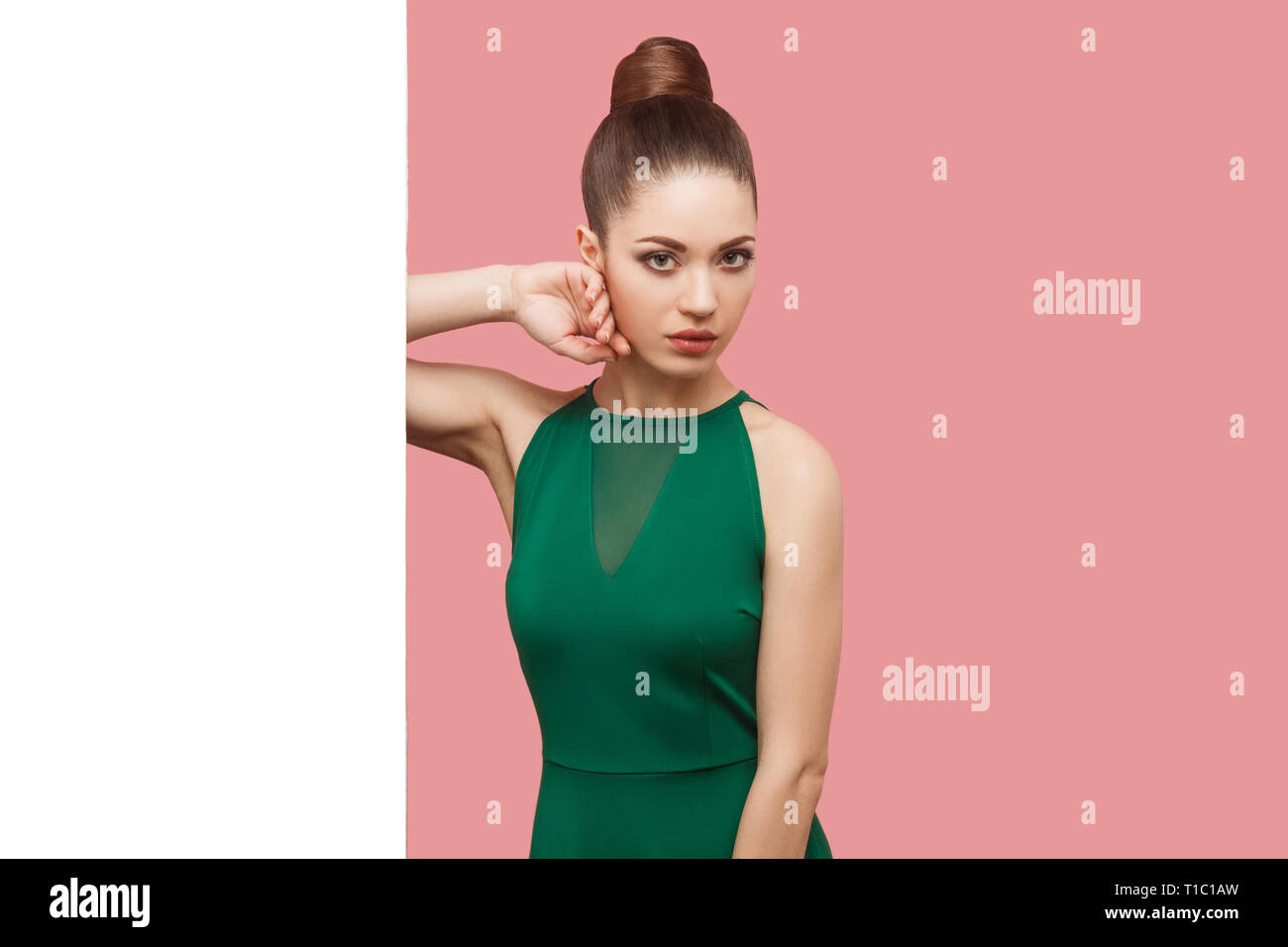 Portrait of serious beautiful young woman with bun hairstyle, makeup in ...