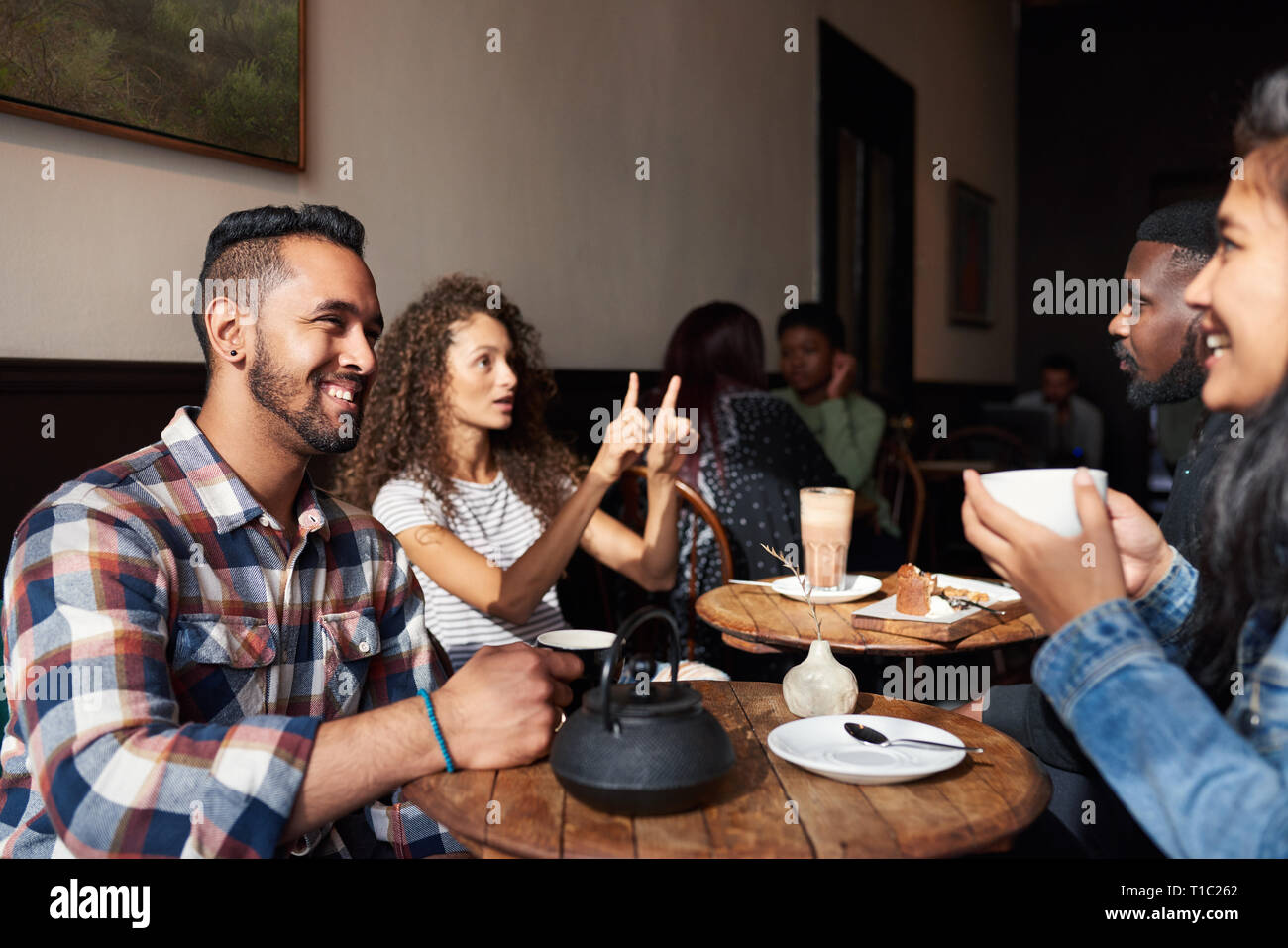 Smiling friends drinking coffee while sitting together in a cafe Stock Photo