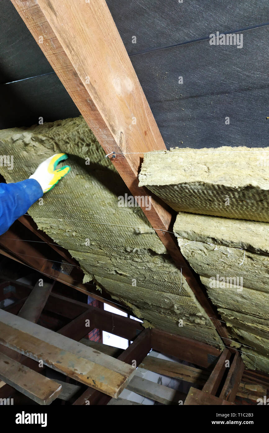 A man installs a thermal insulation layer of a thermal roof - using ...