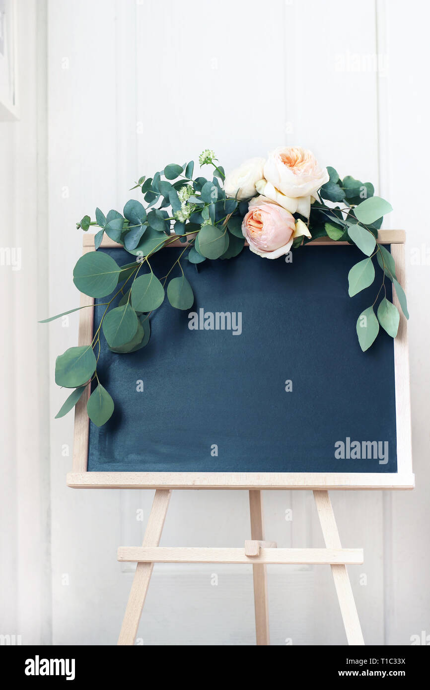 Empty wedding chalkboard sign mockup scene. Floral garland of eucalyptus branches and apricot English roses flowers. Rustic birthday party decoration, Stock Photo