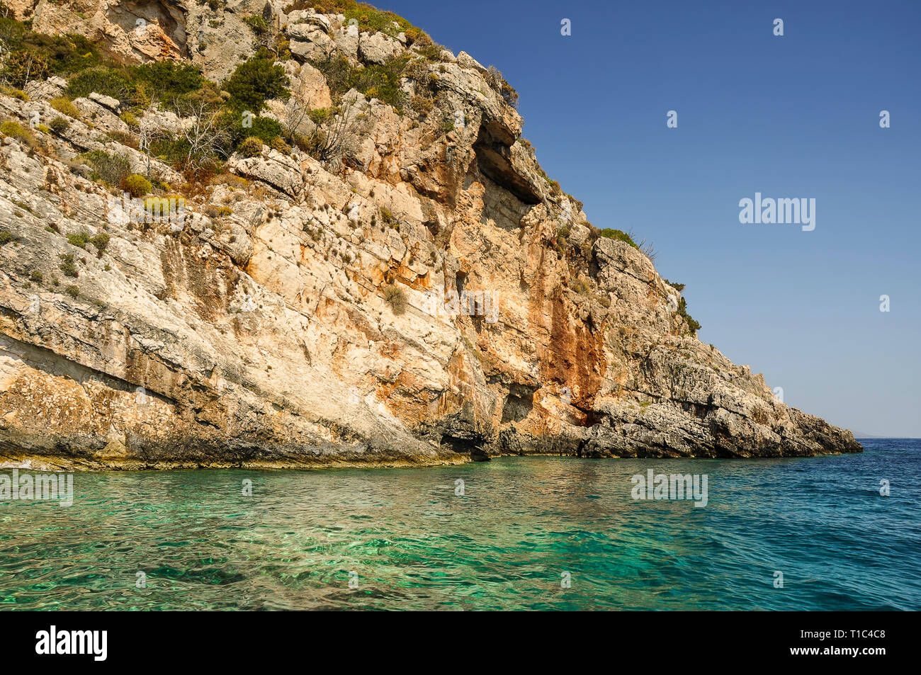 Beautiful and colorful view of rock coastline and crystal, blue sea on sunny day. Small stone cliff ideal for jump into turquoise water during vacatio Stock Photo