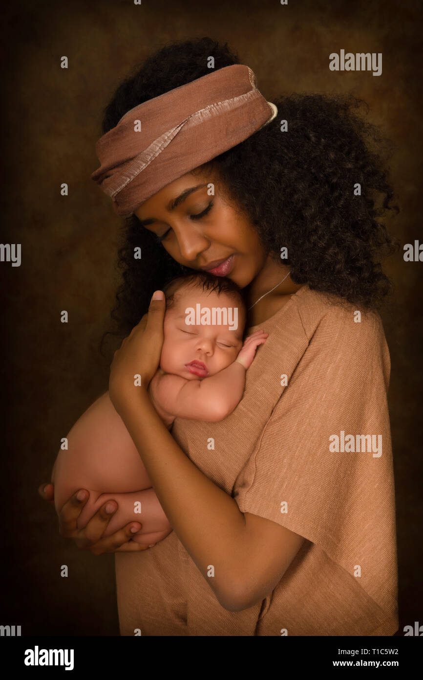 Ethiopian young mother holding her 7 days old little baby against a dark background Stock Photo