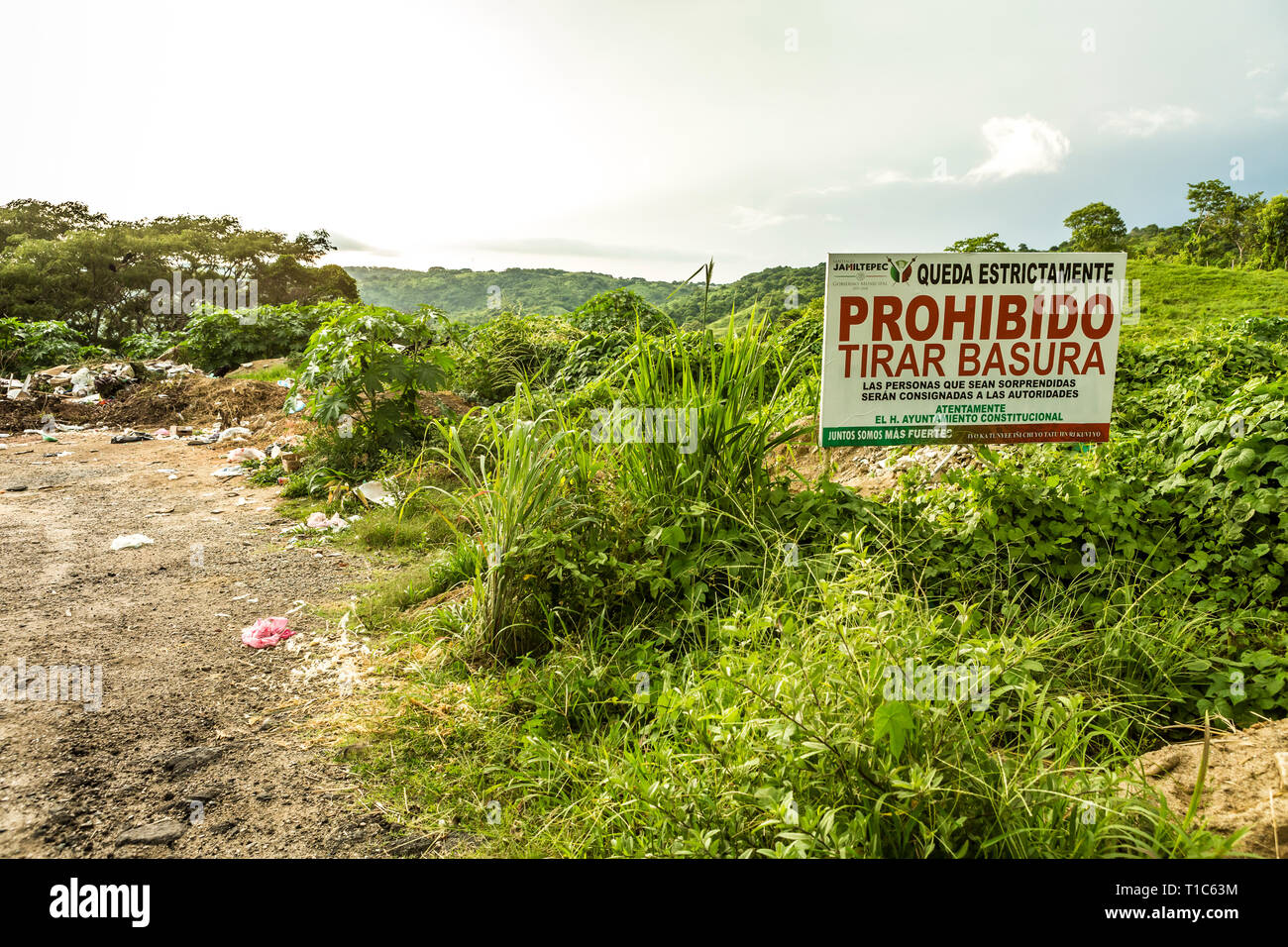 Contrast of a roadside dumping ground next to government sign saying 'No dumping' Stock Photo