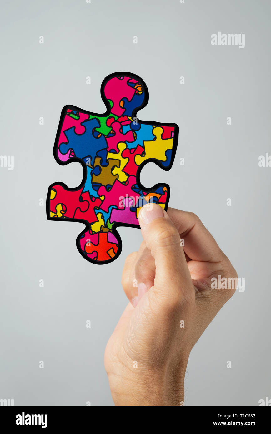 closeup of a man with a puzzle piece patterned with many puzzle pieces of different colors, symbol of the autism awareness, on a white background Stock Photo
