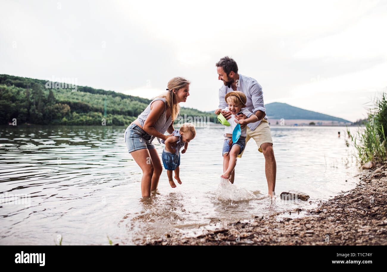 A young family with two toddler children outdoors by the river in summer. Stock Photo