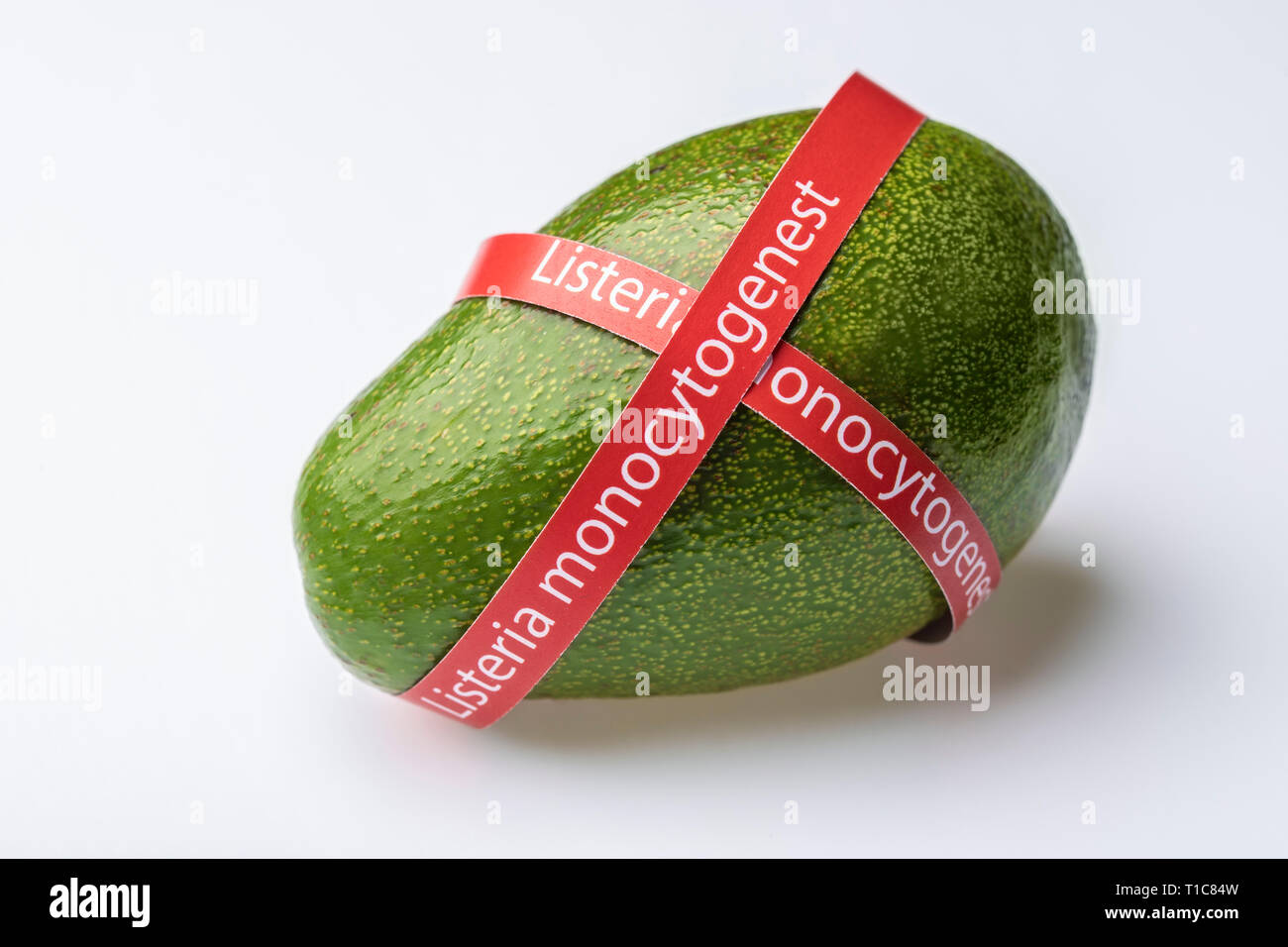 Ripe avocado entwined with ribbon with text Listeria monocytogenes . Consumer safety concept. Stock Photo