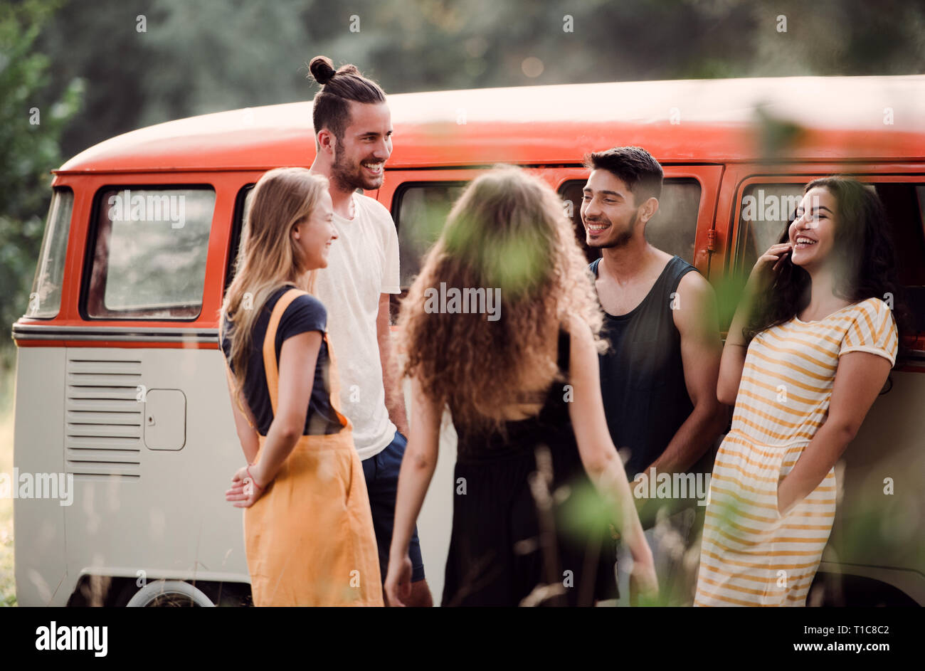A group of young friends on a roadtrip through countryside, laughing ...