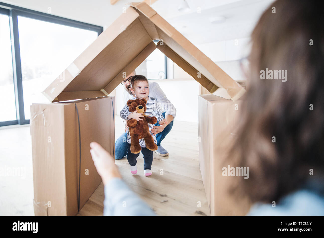 A young family with a toddler girl indoors, moving in new home concept. Stock Photo