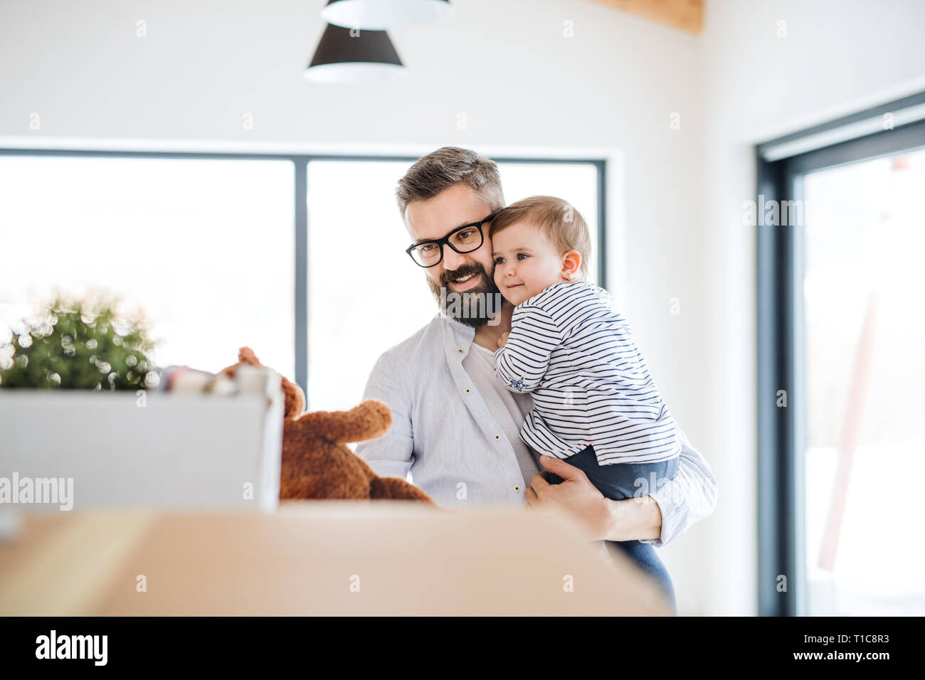 A portrait of young father with a toddler girl moving in new home. Stock Photo