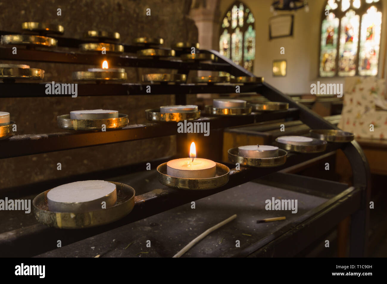 Votive candles lit as prayers for loved ones inside a Christian church Stock Photo