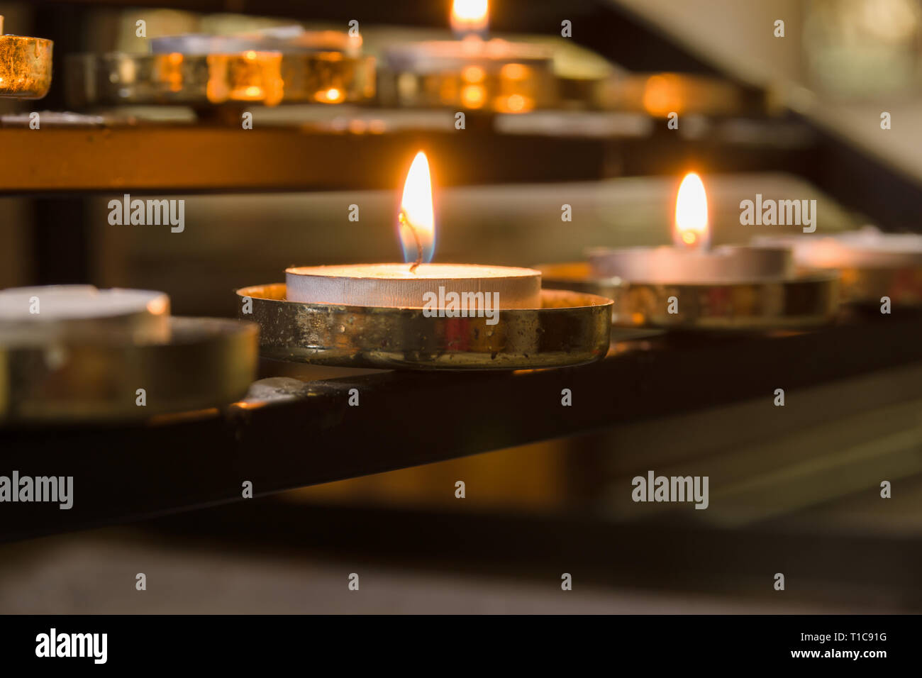 Votive candles lit as prayers for loved ones inside a Christian church