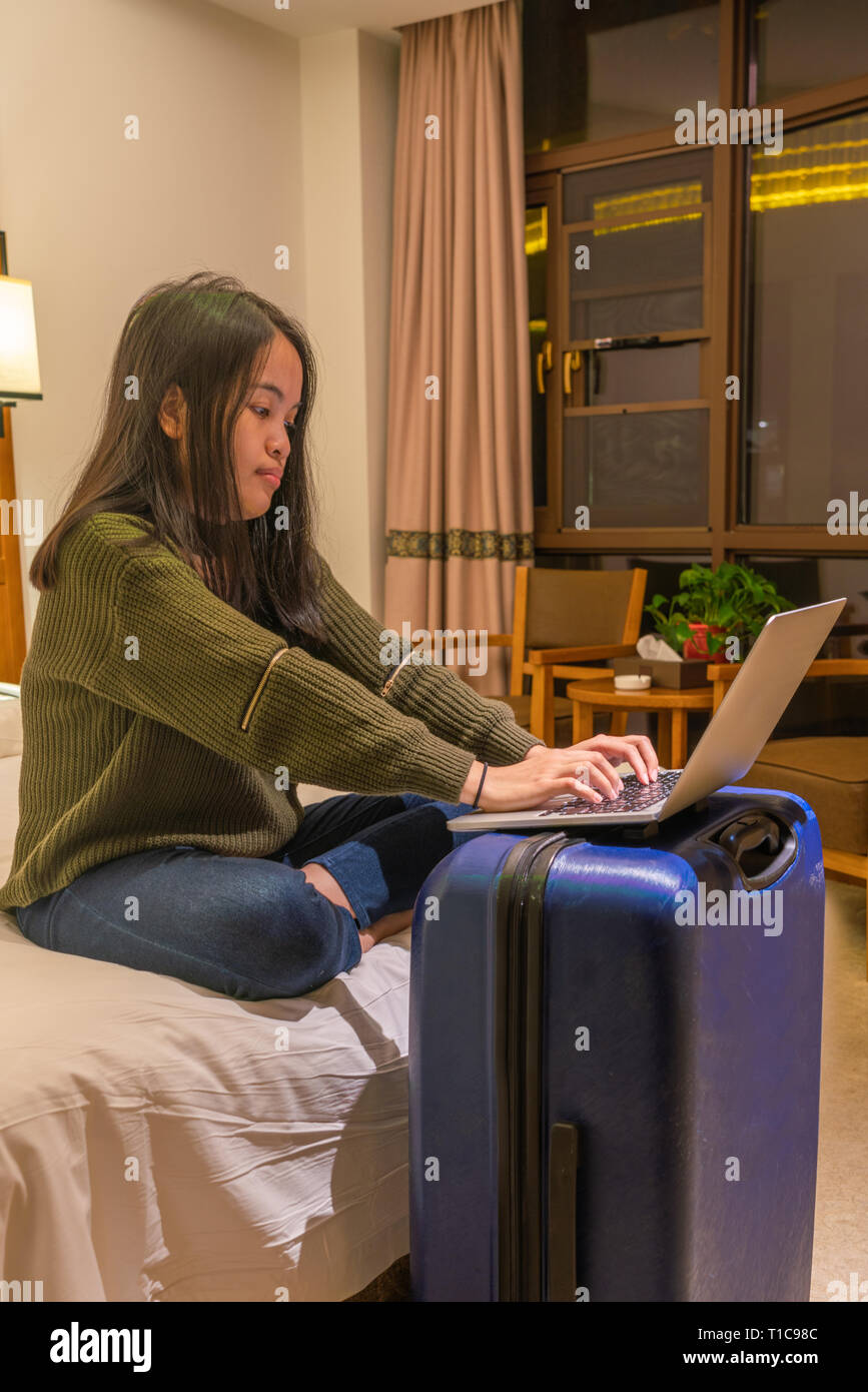 Woman putting laptop on suitcase and working Stock Photo