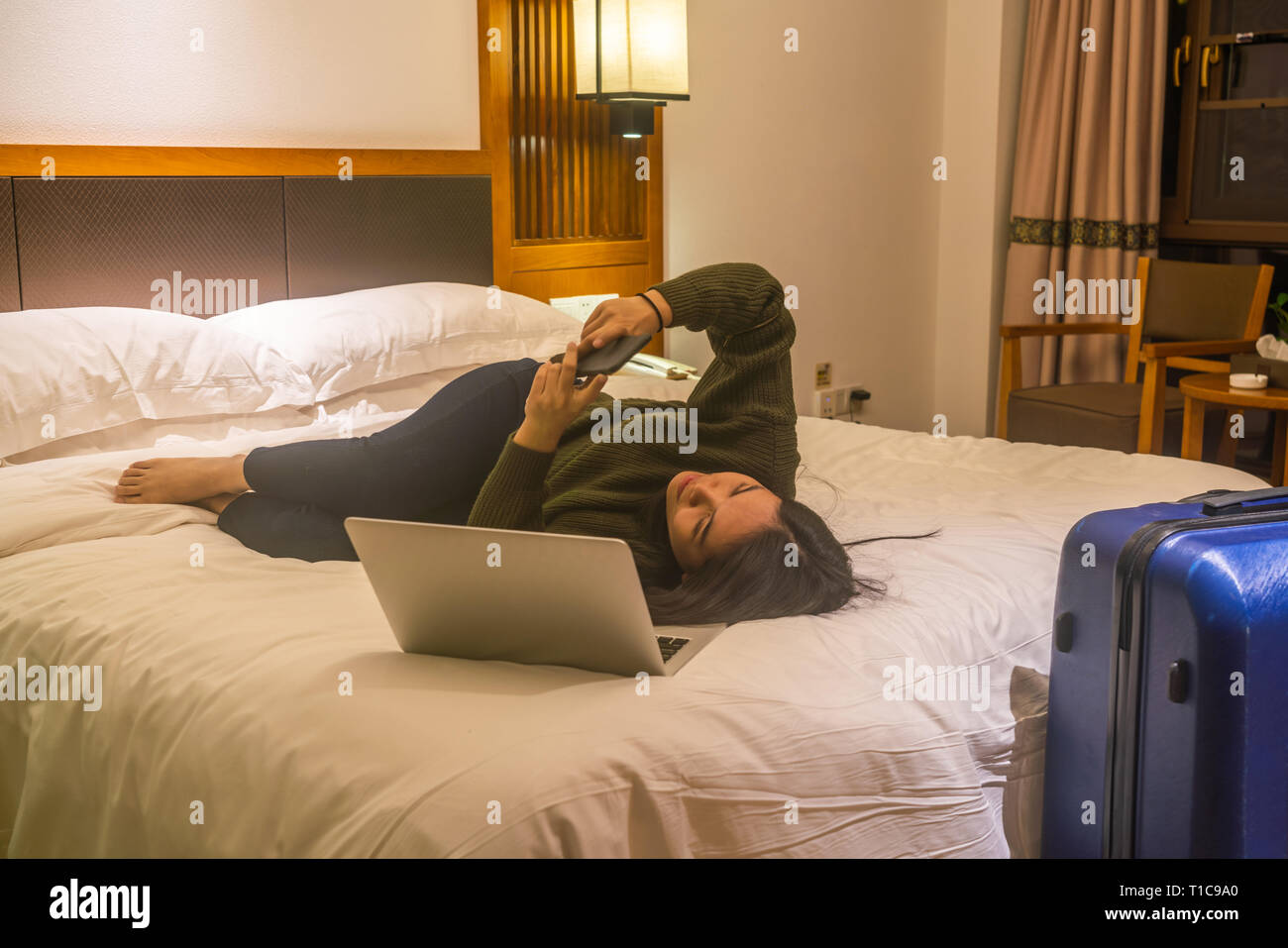 Young woman lying on bed and using smartphone Stock Photo