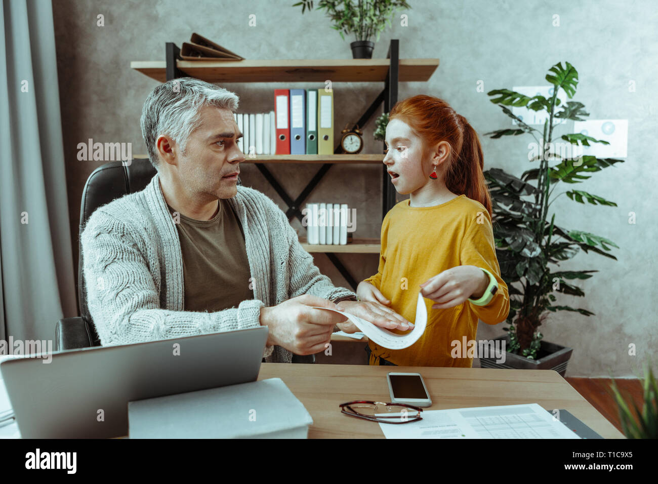 Cute red haired girl talking to her father Stock Photo