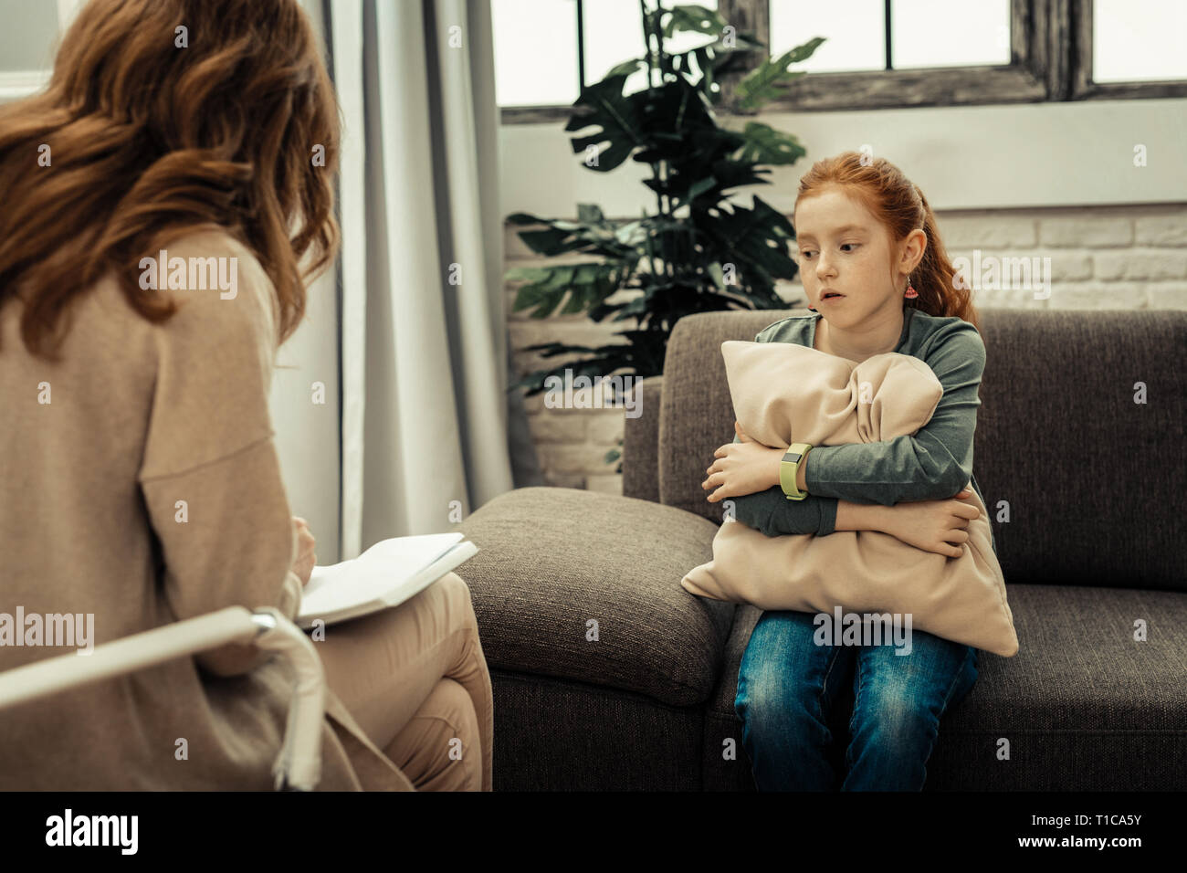 Cheerless gloomy young girl undergoing psychological treatment Stock Photo