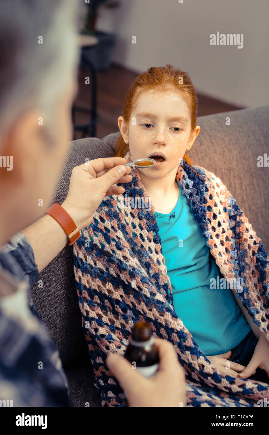 Nice pale girl taking the cough mixture Stock Photo