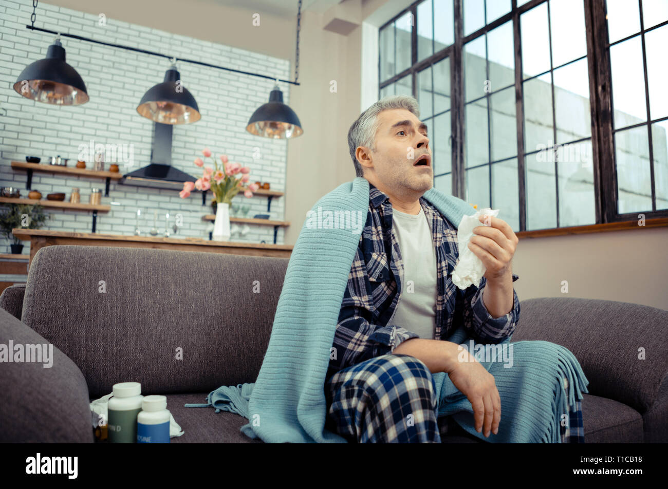 Gloomy ill man being ready to sneeze Stock Photo