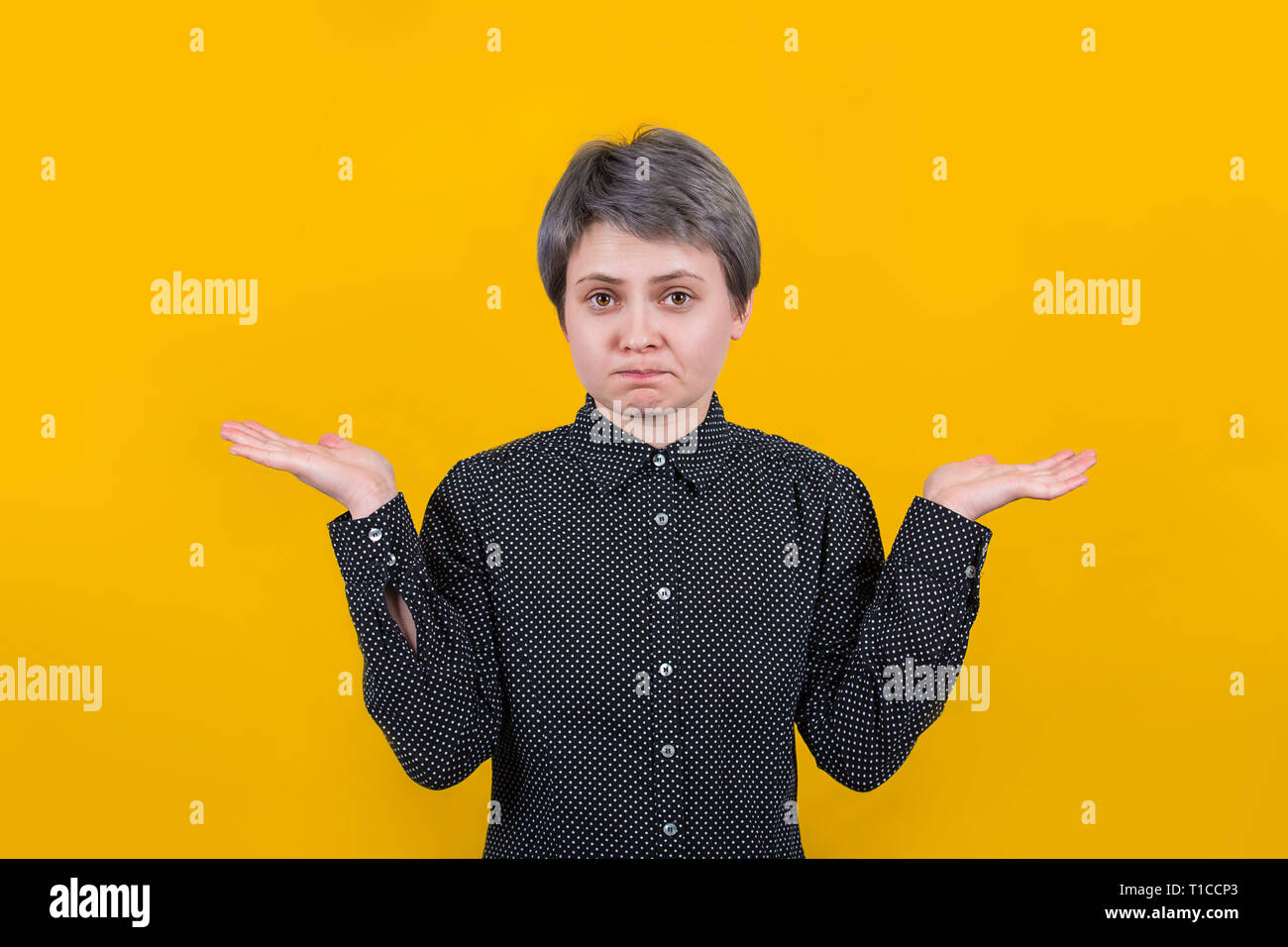 Clueless puzzled woman with widely opened eyes having hesitation shrugging her shoulders expressing uncertainty. Facial expressions, life perception a Stock Photo