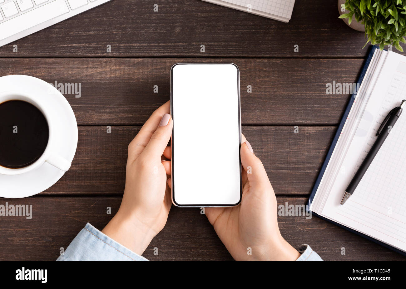 Woman using blank smartphone on workplace desk Stock Photo