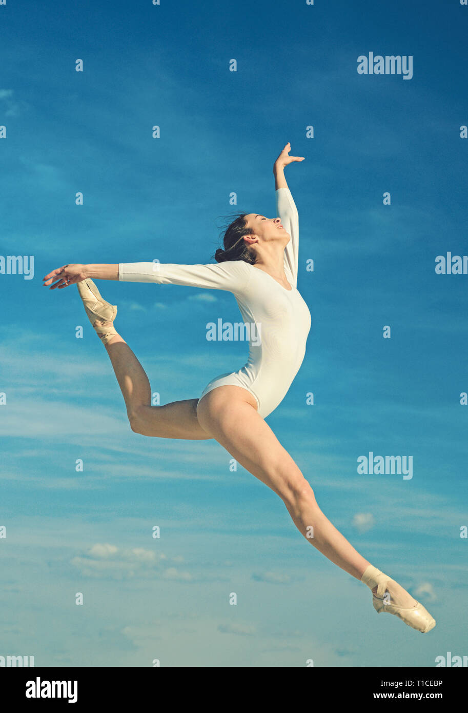 Grace and beauty. Classic dance style. Young ballerina jumping on blue sky. Cute ballet dancer. Pretty woman in dance wear. Practicing art of Stock Photo