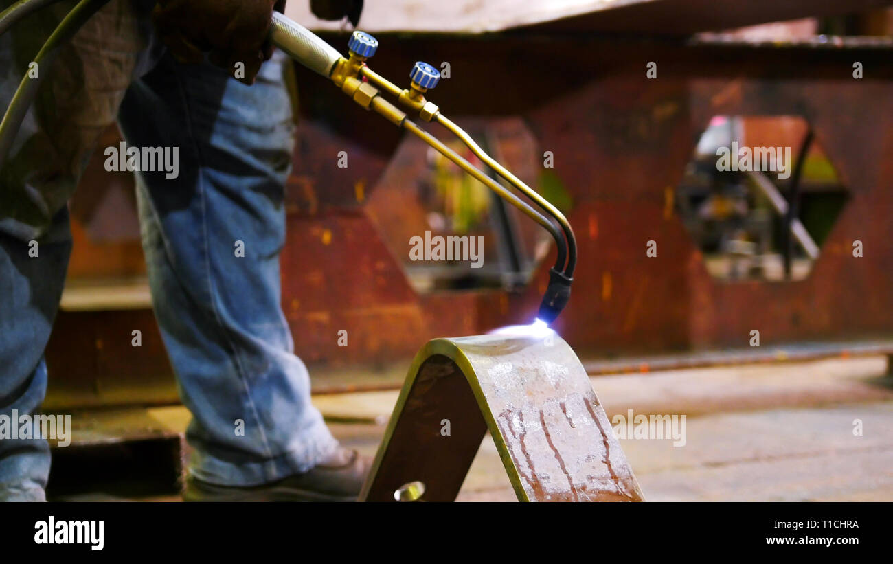Construction plant. A man worker heating up the detail with a gas