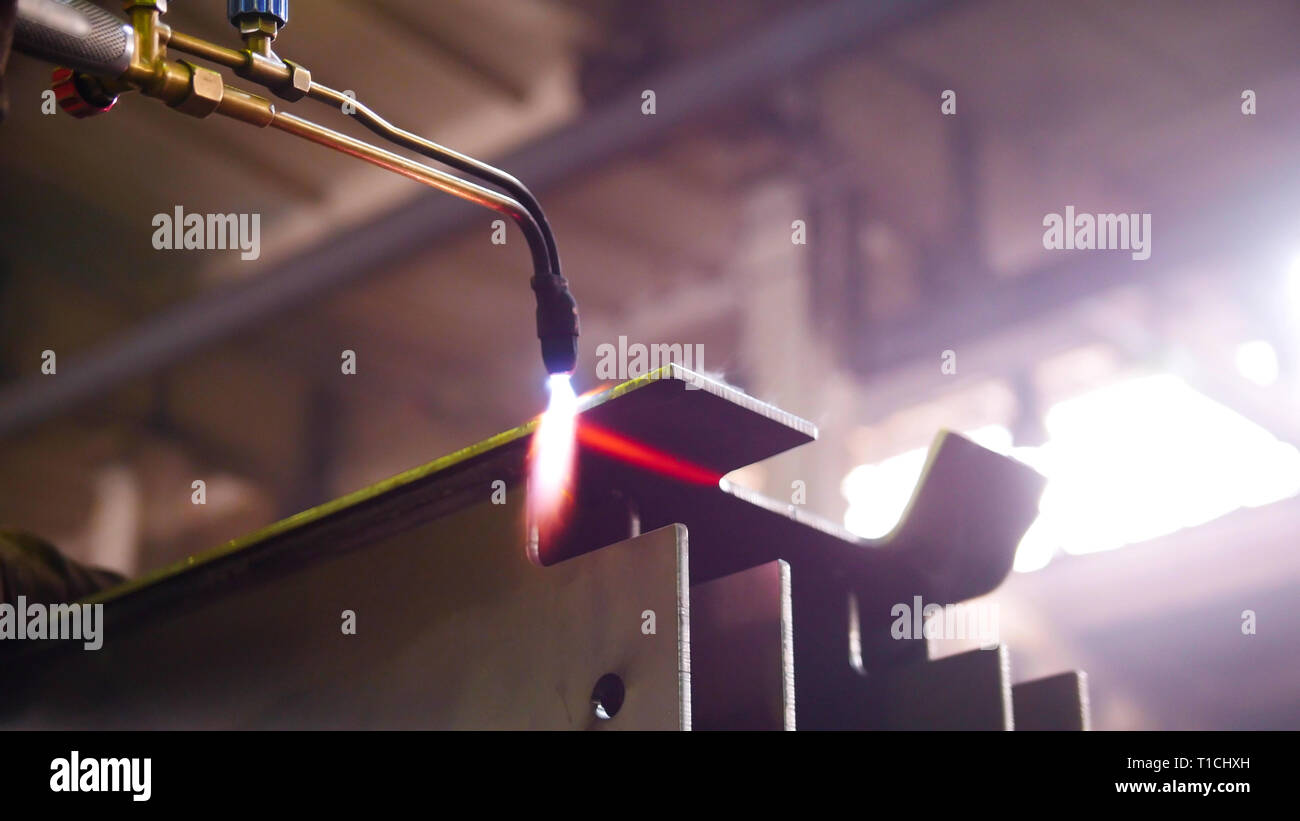 Construction plant. A worker heating up the detail with a gasburner