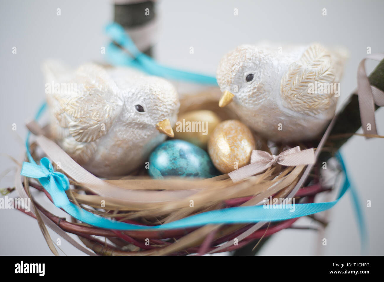 Two cute handmade small easter birds and their golden eggs in nest , parenting , adoption , care concept Stock Photo