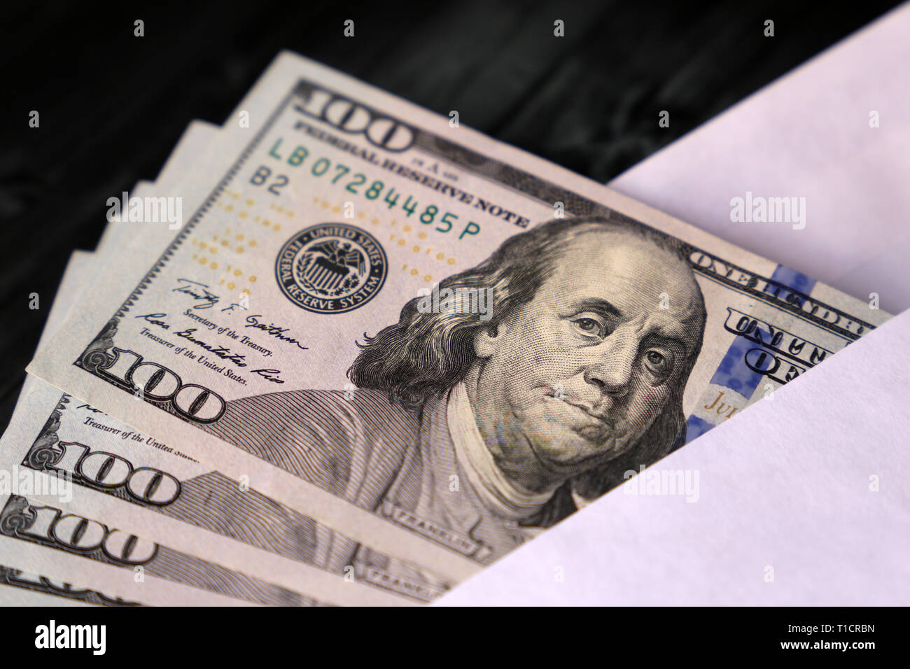 US dollars bills in the envelope on the wooden table. Income, bonus or bribe concept Stock Photo