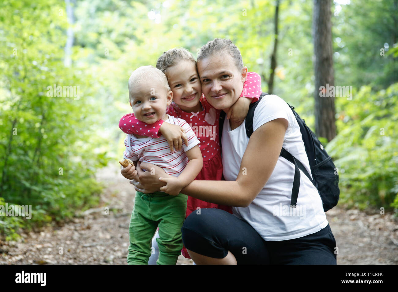 Devoted mother hugging her son and daughter, enjoying the outdoor. Family love and bonding, active lifestyle, mothers day concept. Stock Photo