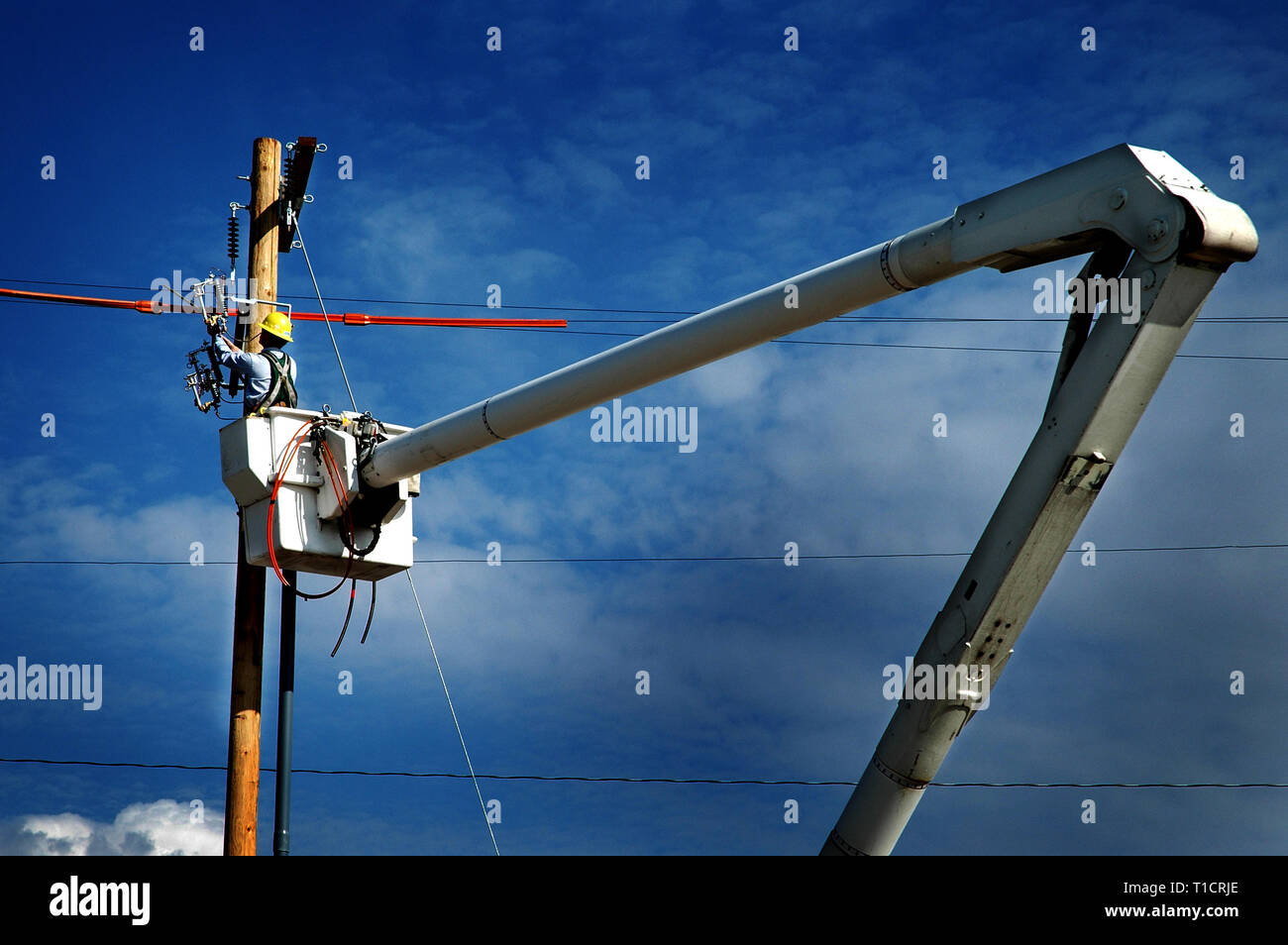 Man working worker on power lines in crane bucket high in the air dangerous work Stock Photo