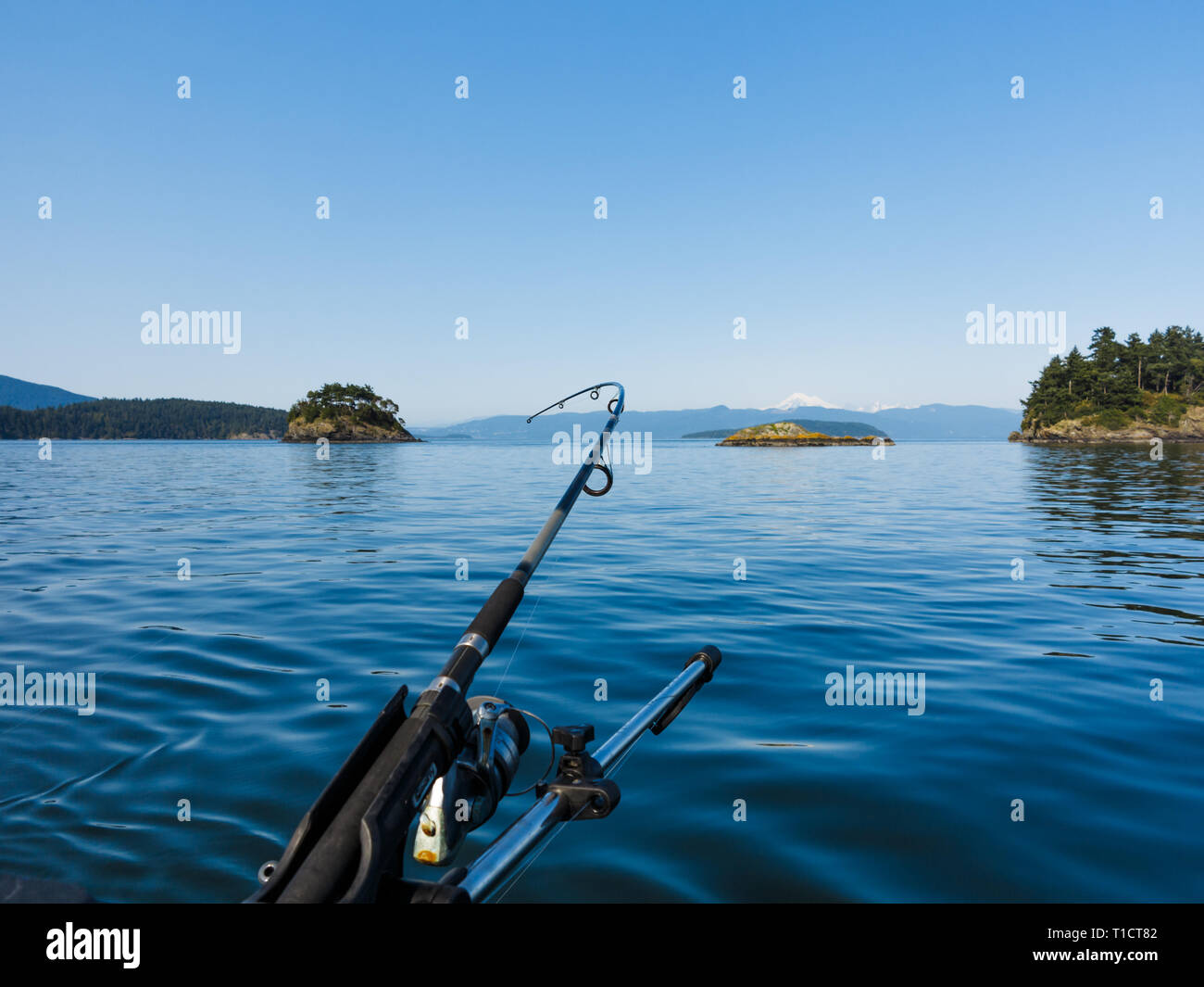 Closeup of fishing rod extending from boat in middle of bay with