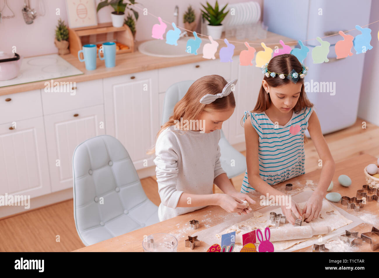 Concentrated sisters forming biscuits for Easter celebration Stock
