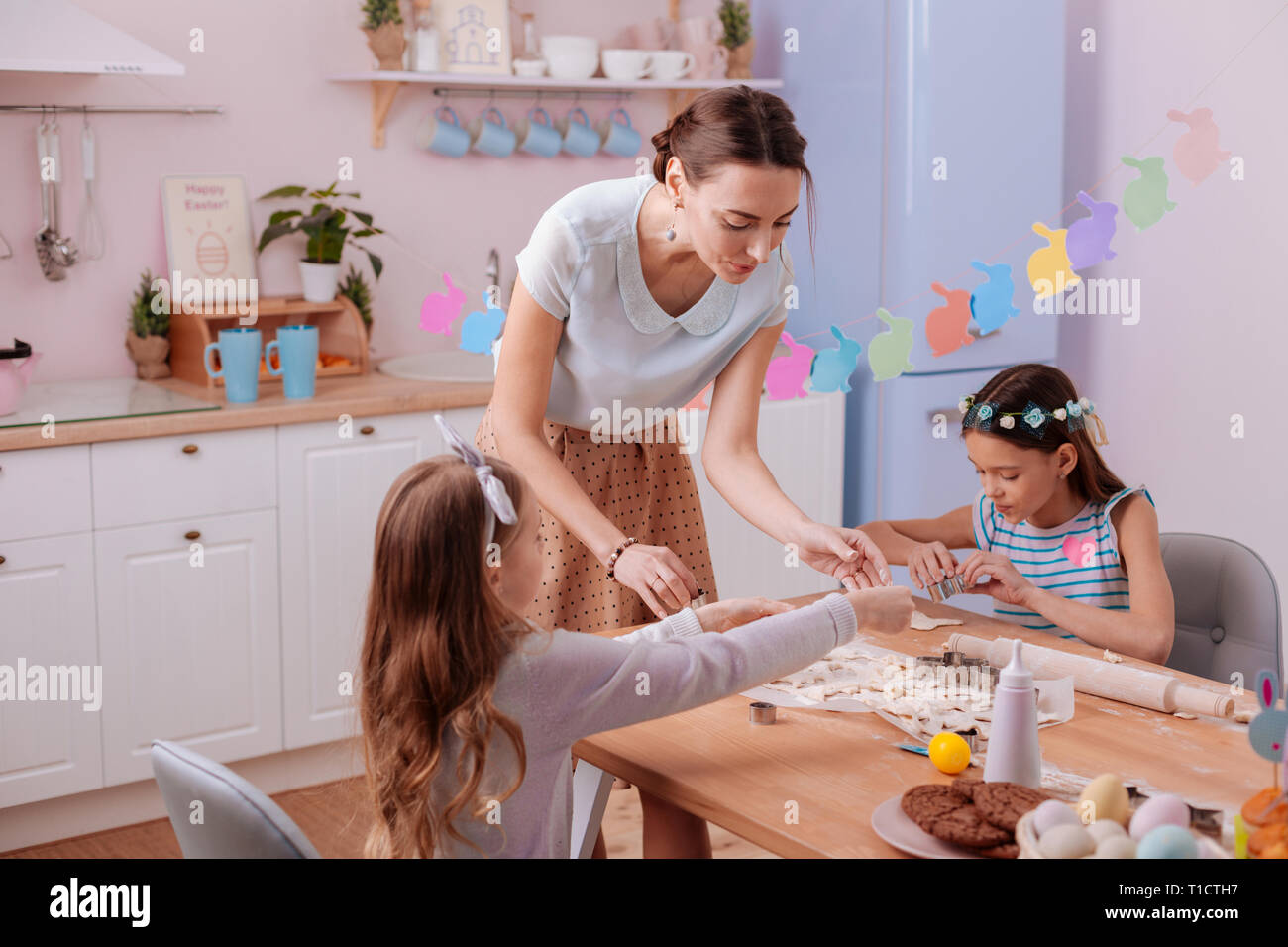 Positive delighted female person helping her daughters Stock Photo