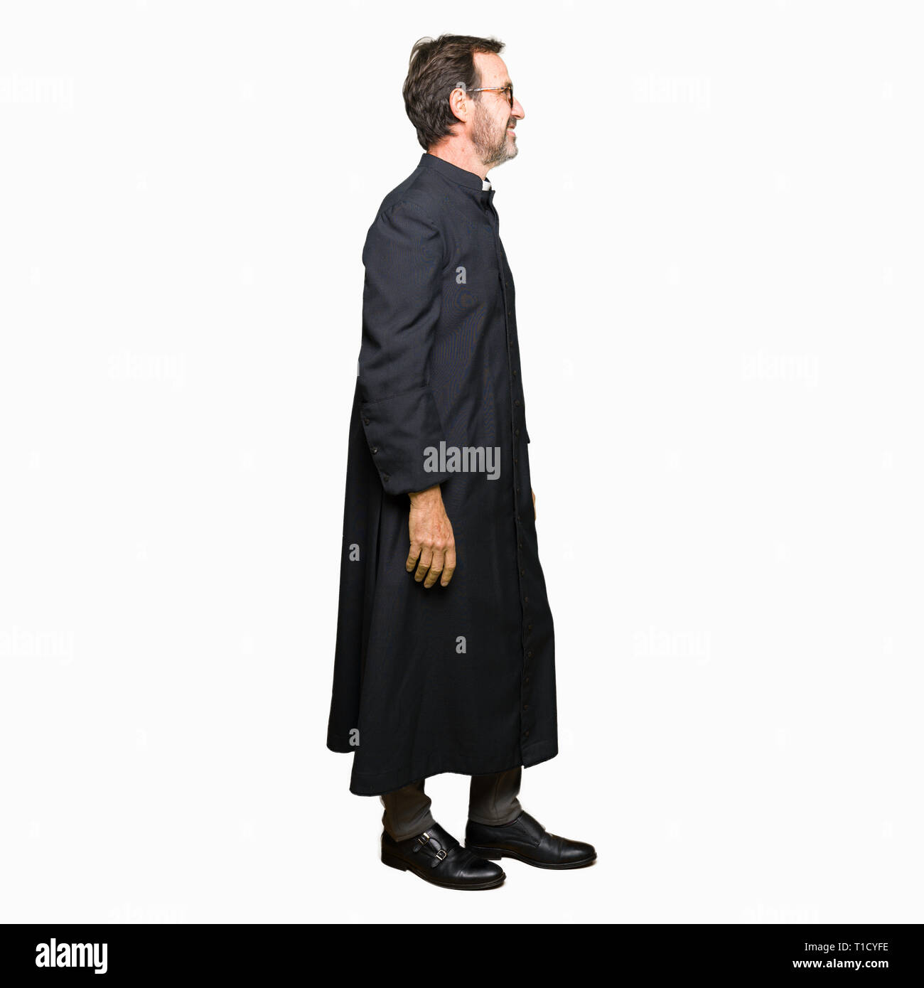 Middle age priest man wearing catholic robe looking to side, relax profile  pose with natural face with confident smile Stock Photo - Alamy