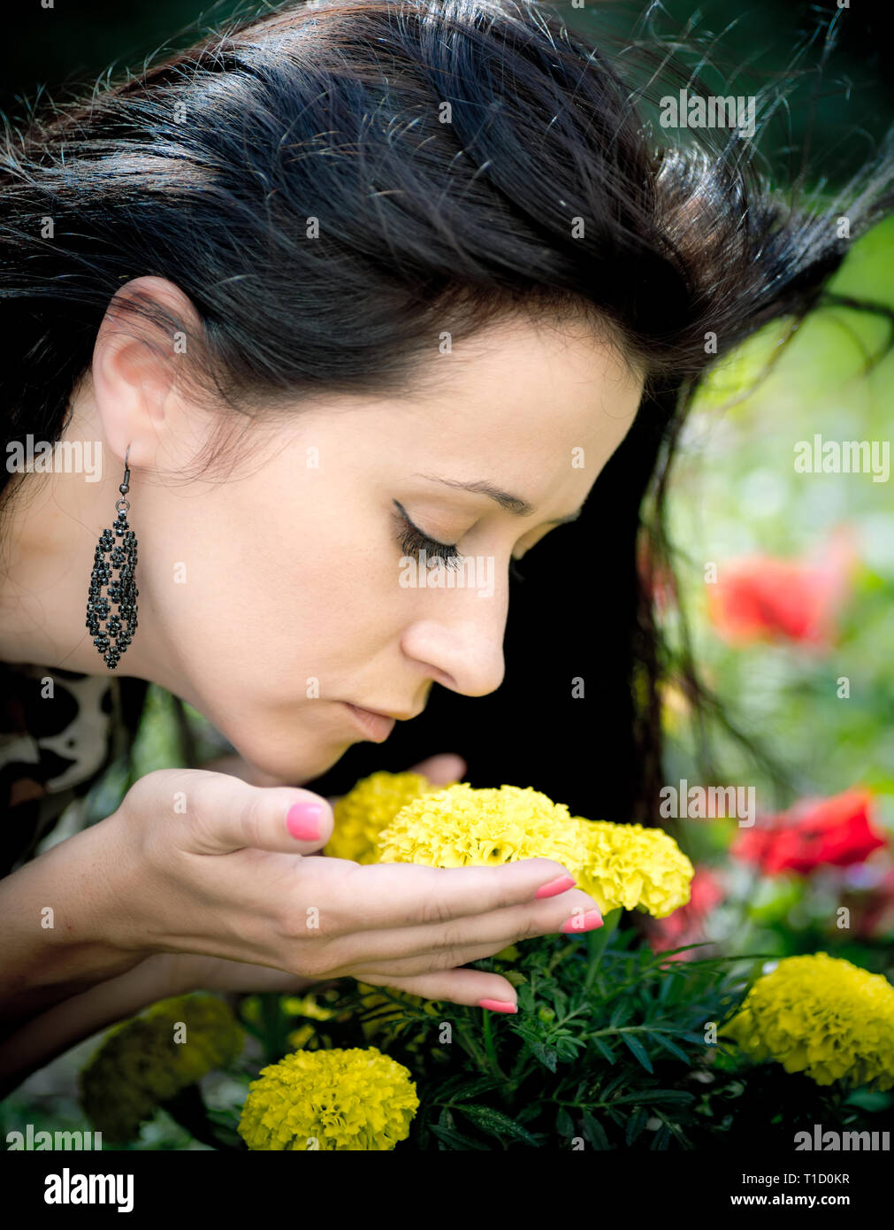 Young beautiful woman smelling yellow flowers in garden Stock Photo Alamy