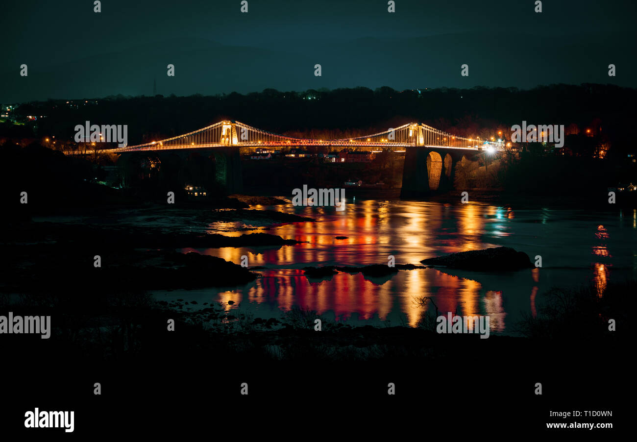 Menai bridge at night with Menai Straight in foreground. Anglesey, Wales Stock Photo