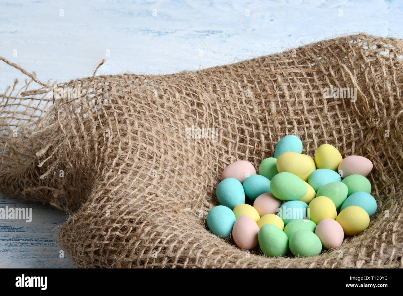 Closeup burlap bird nest with easter candy eggs Stock Photo