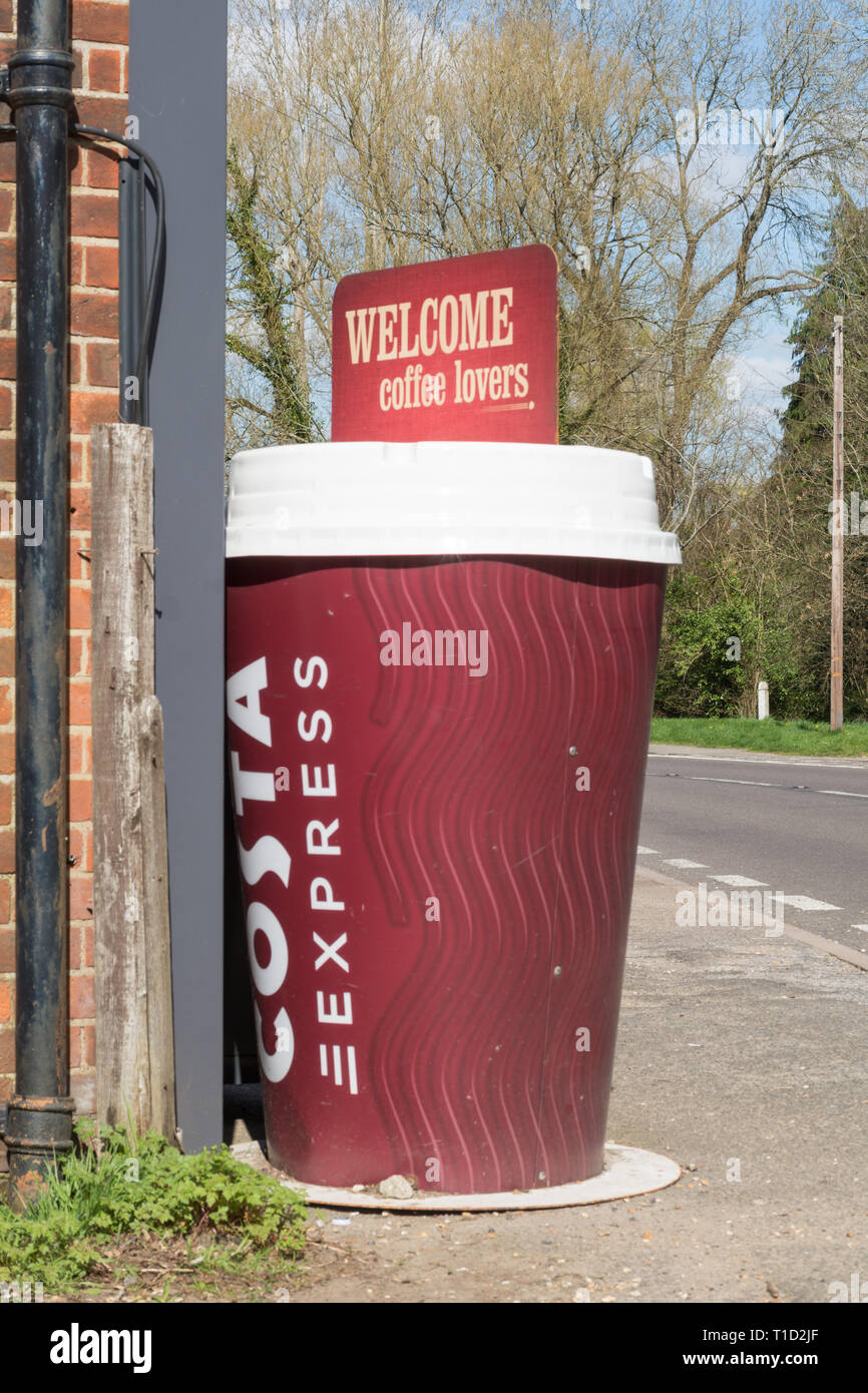 Large model of a takeaway Costa coffee cup with the slogan welcome coffee lovers advertising the brand outside a village shop in Surrey UK Stock Photo