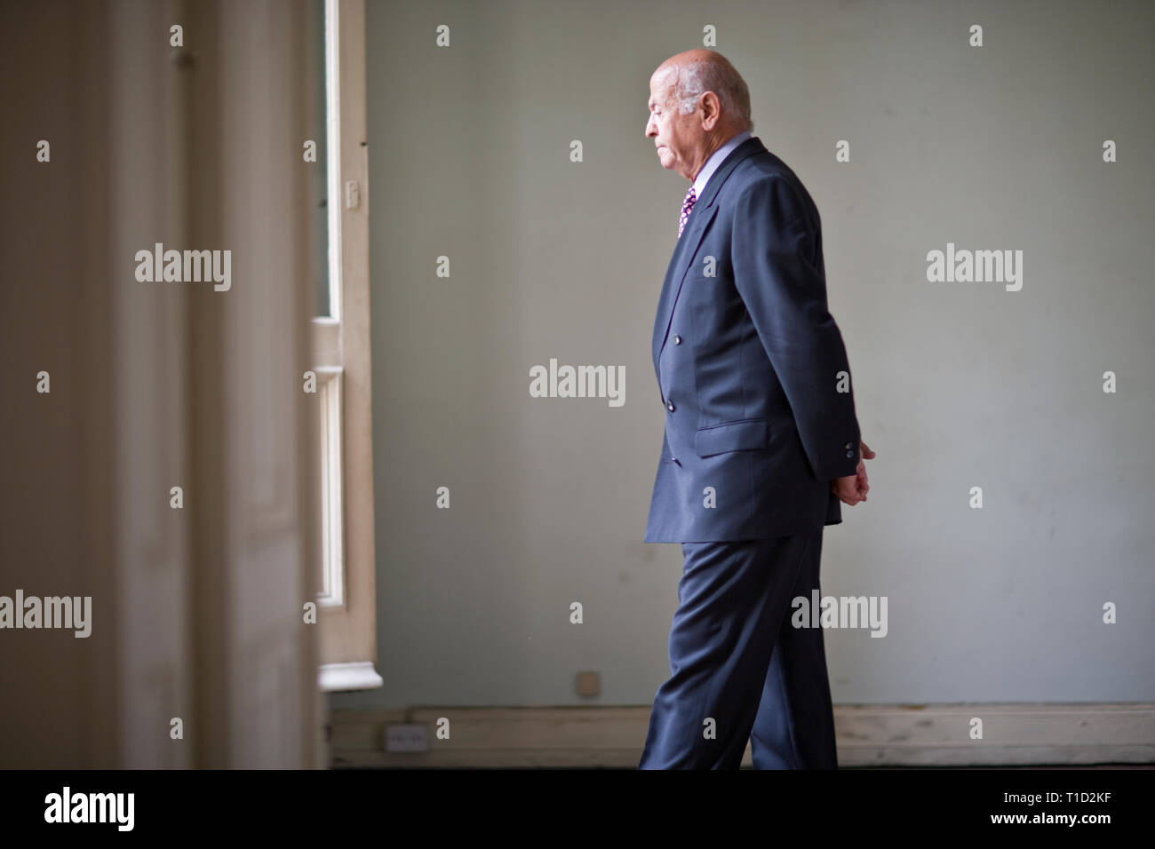 Senior man walking with his hands behind his back in a room Stock Photo