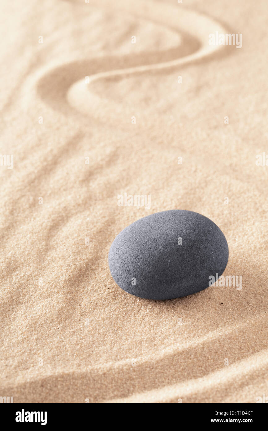 Zen stone Japanese sand garden round rock in sand. Buddhism or yoga background for spiritual purity and concentration. Stock Photo