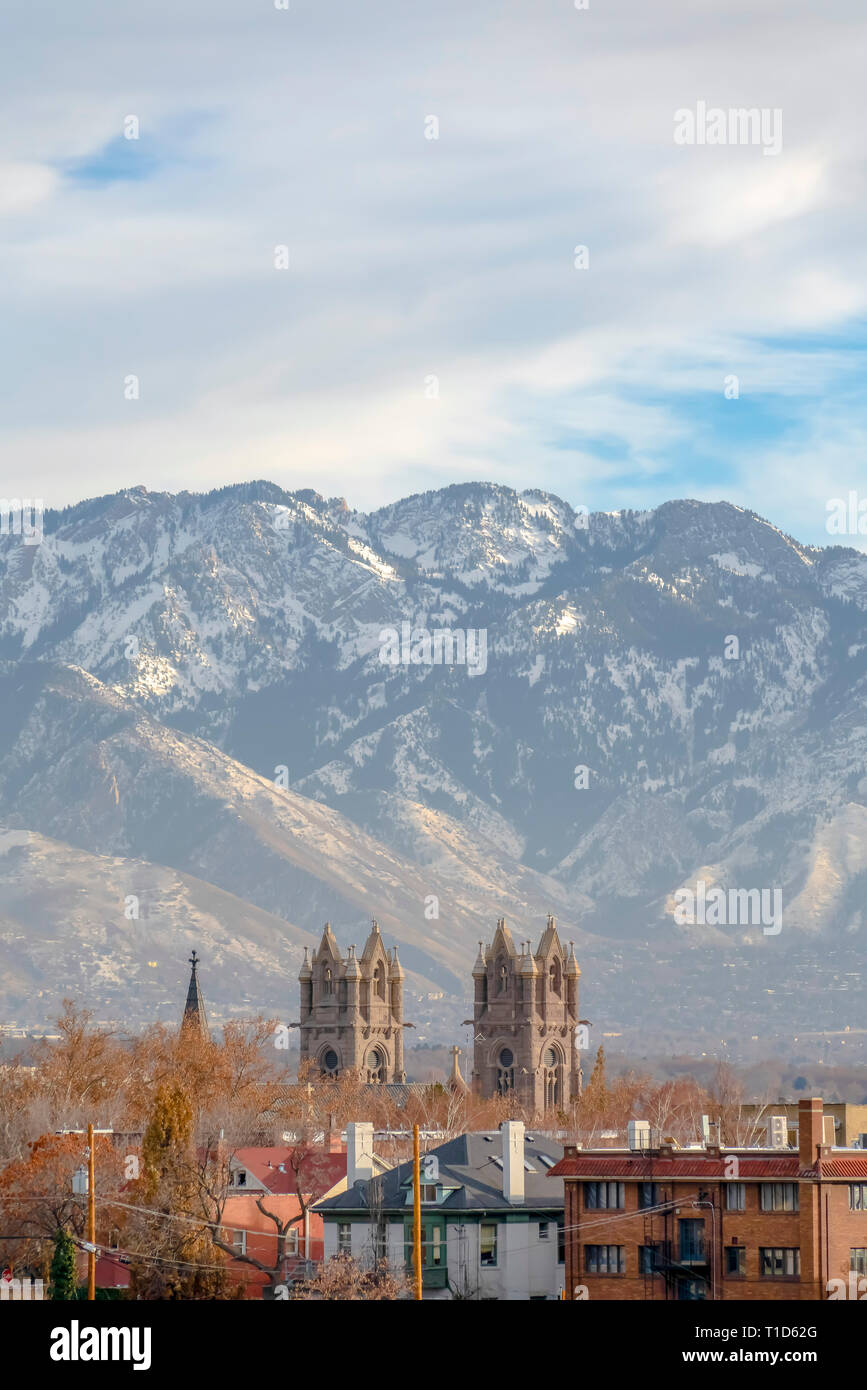 Cathedral of the Madeleine and mountain in Utah. Buildings in Salt Lake City with view of iconic Cathedral of the Madeleine. Snowy Wasatch Mountain ag Stock Photo