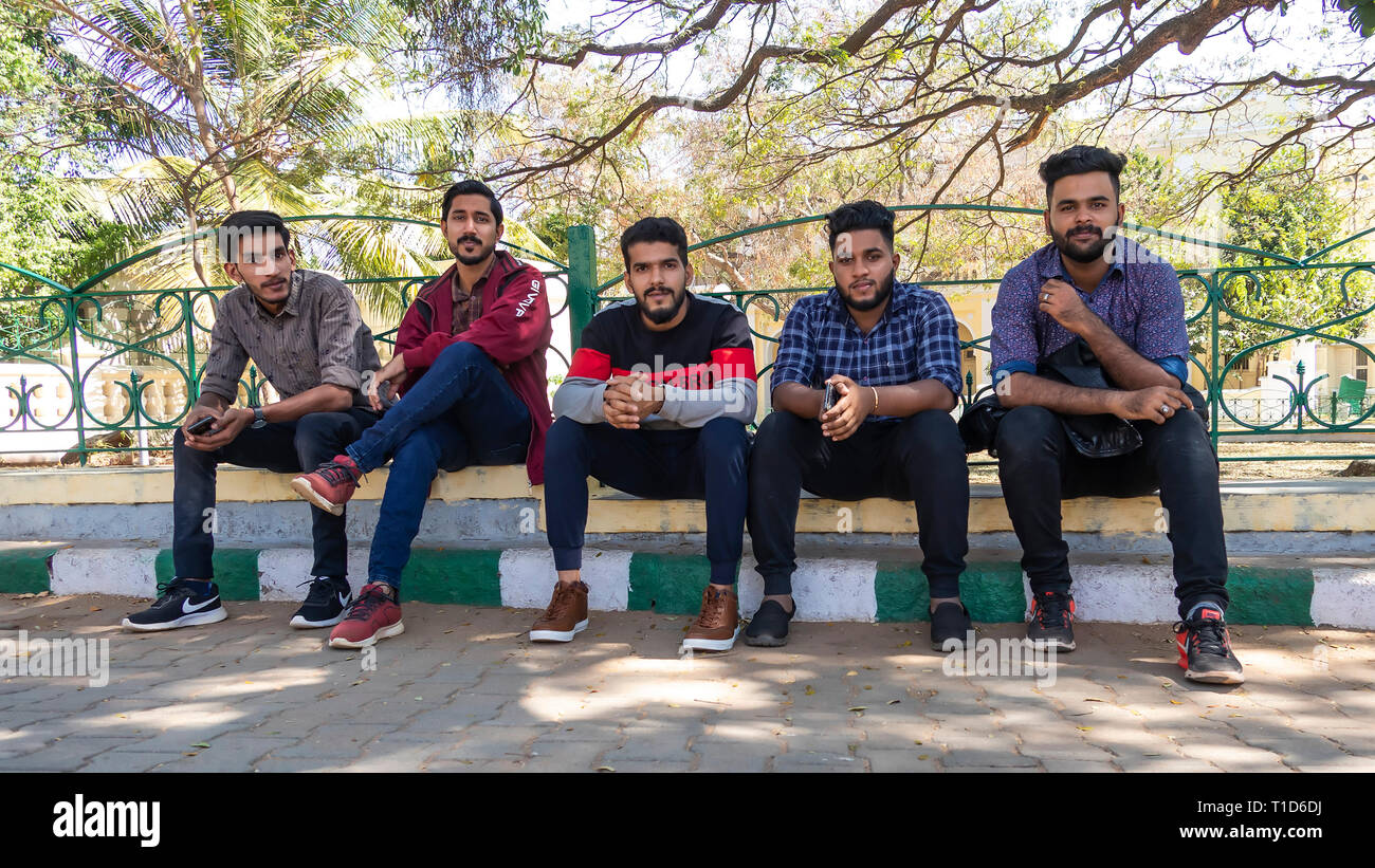 Five young Indian men sitting on the sidewalk Stock Photo