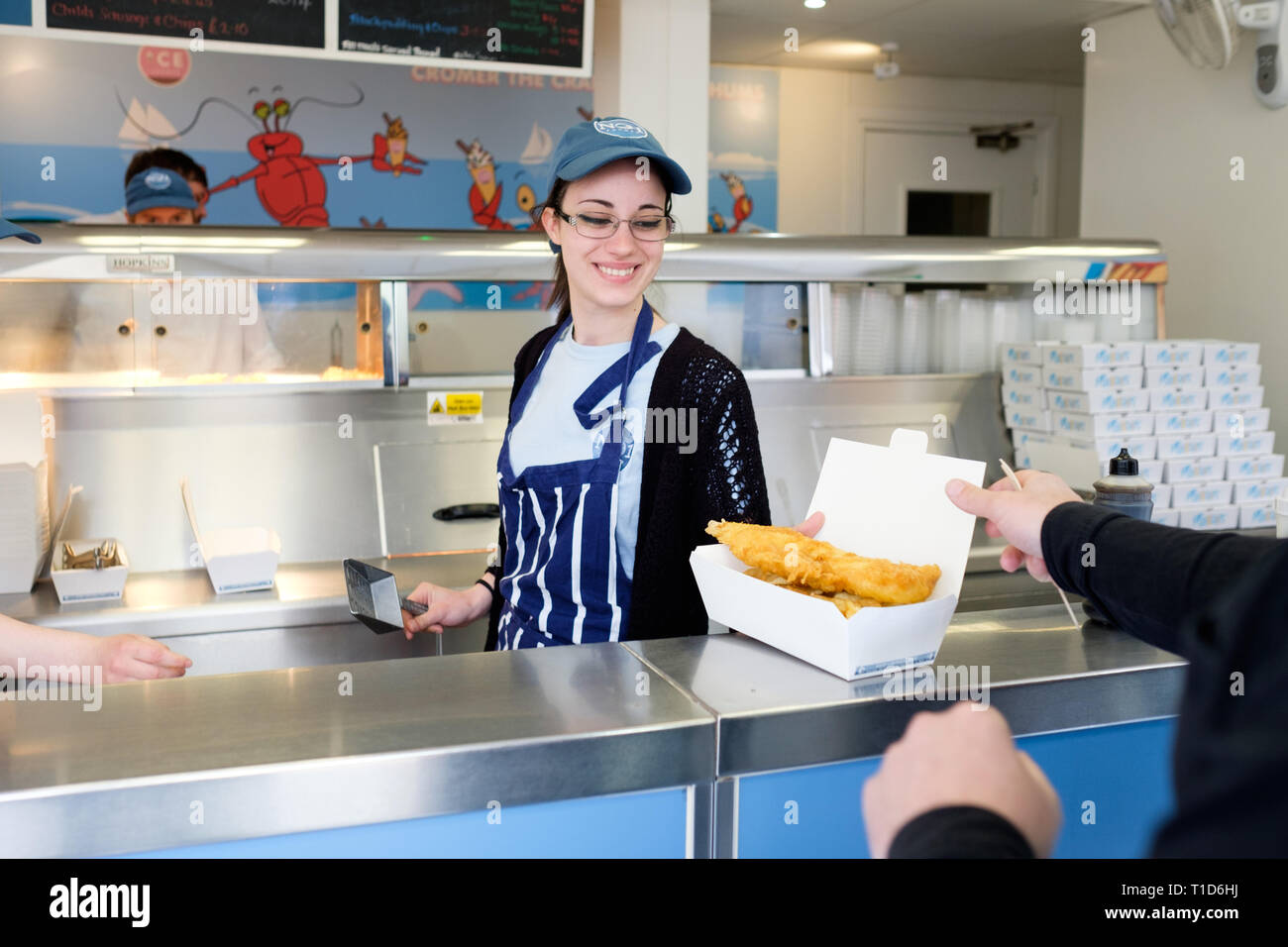 Friendly staff serving tasty fish and chips at No1 Fish & Chips Shop in Cromer, North Norfolk, England. Stock Photo