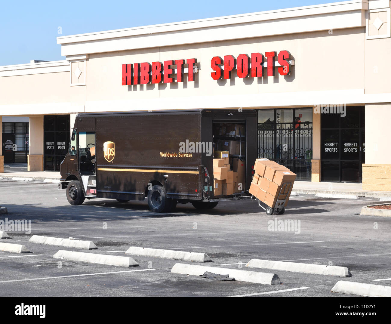 Ups delivery driver unloading truck at hibbett sports store at strip